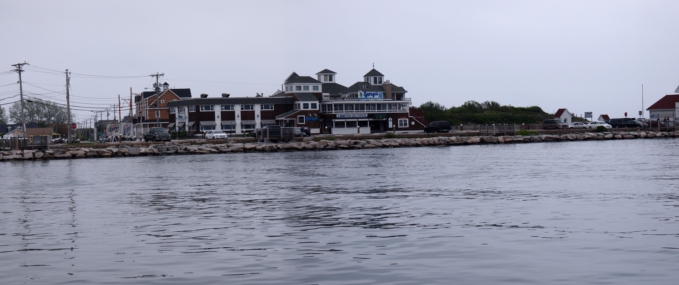 [Two photos stitched together showing building on the shore with water in the foreground.]